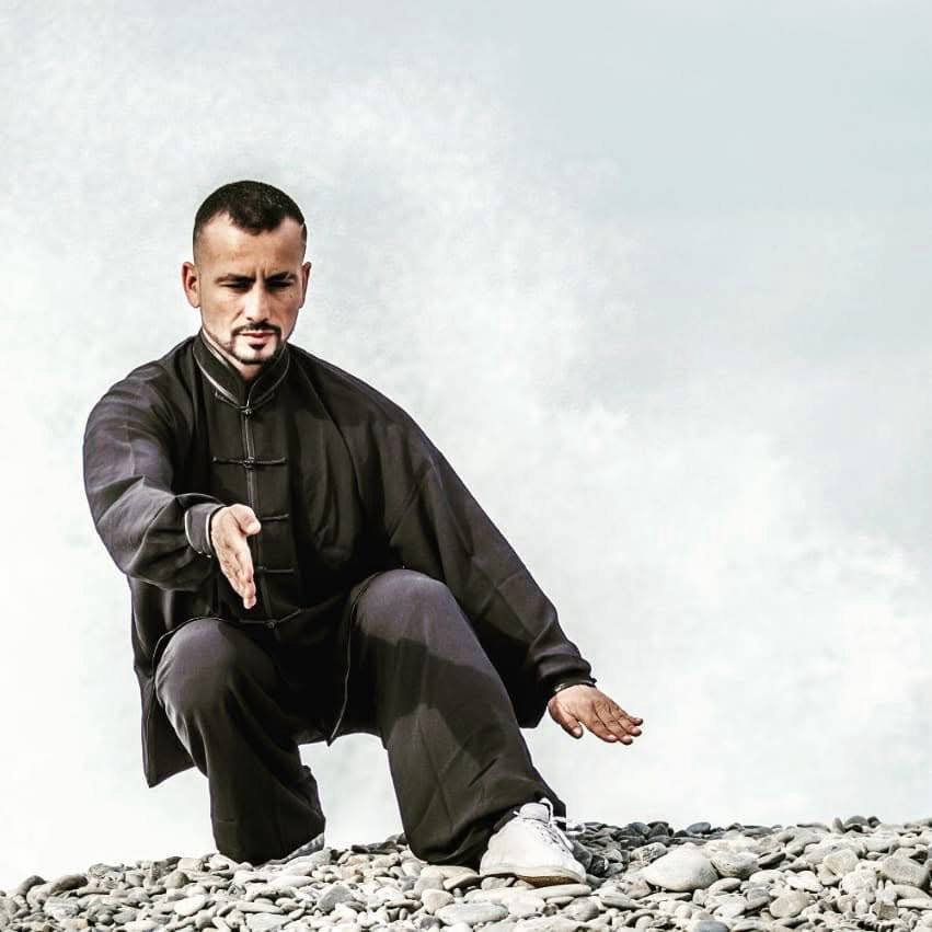 John Sammut performing kata on pebble shore, sky background